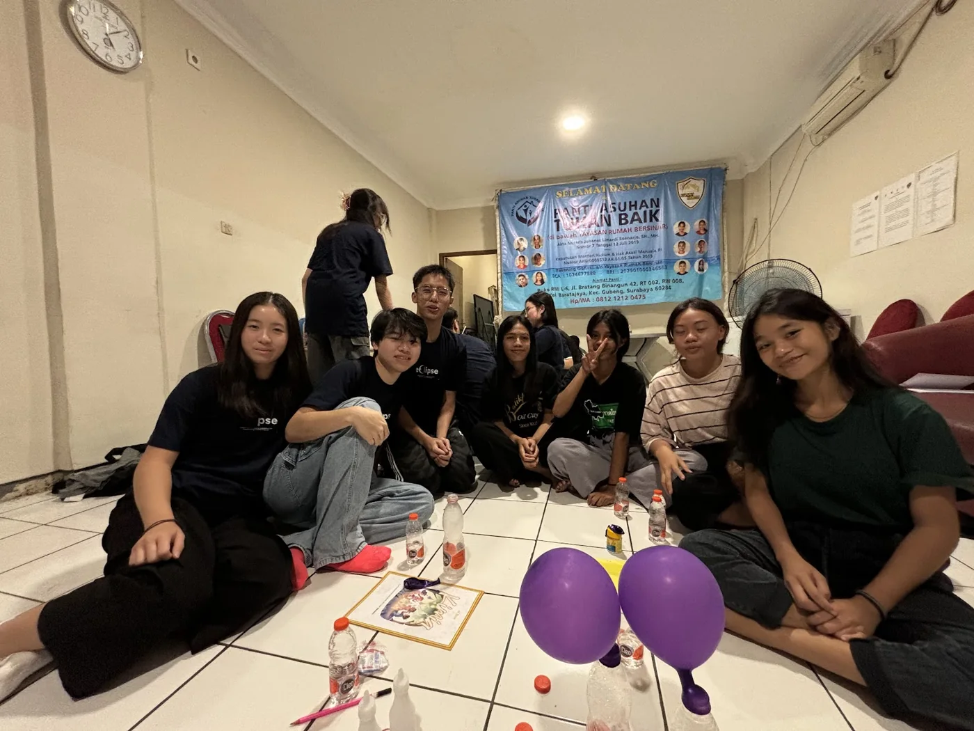 Children and volunteers gathered with workbooks and purple balloons.