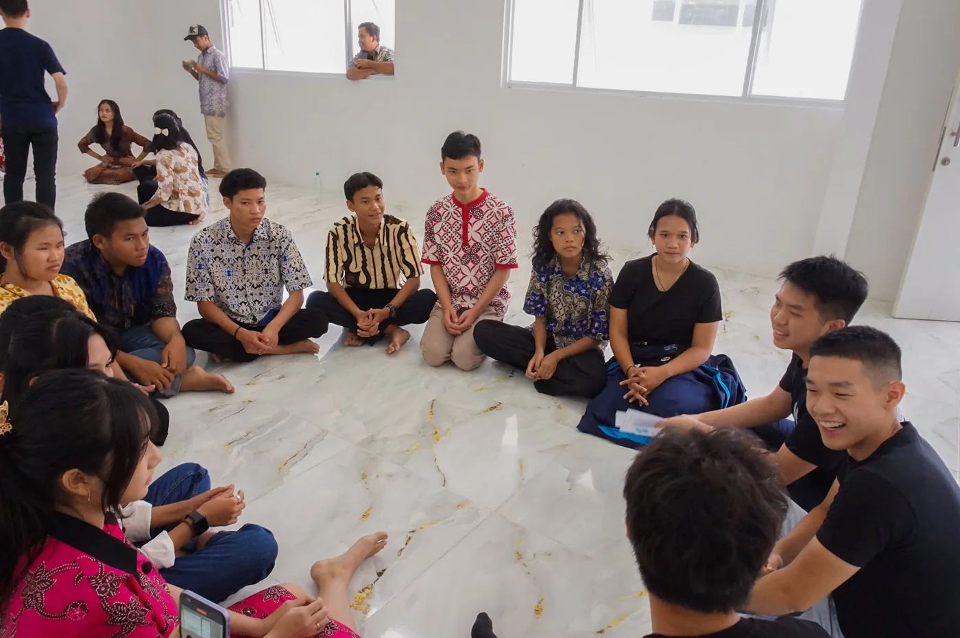 Students and volunteers sitting in a circle during the SMK Tanoko visit.