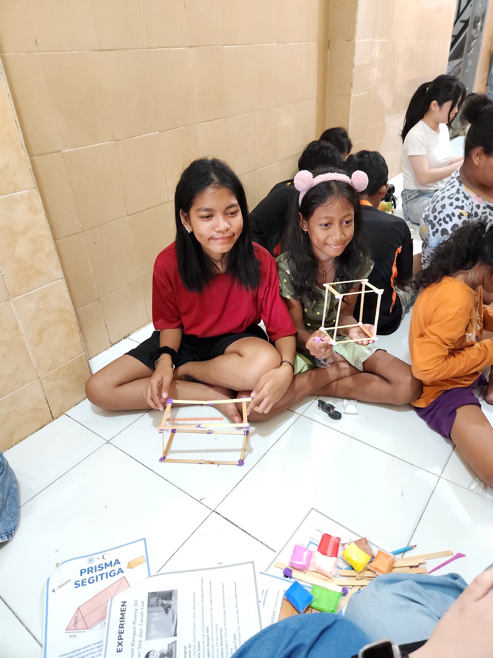 Children building a model alongside a volunteer